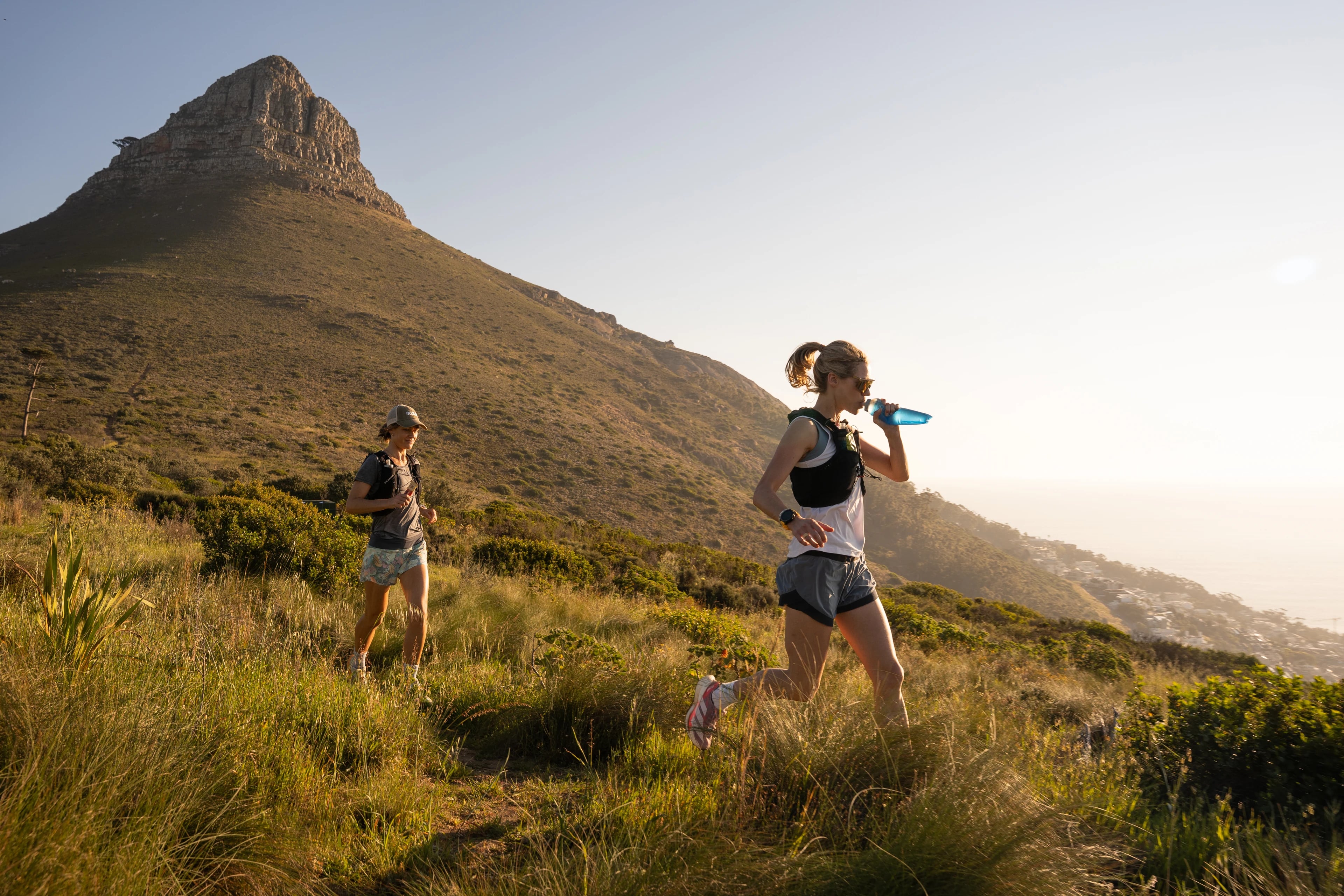 Two trail runners below Lion’s Head in the golden Cape Town light